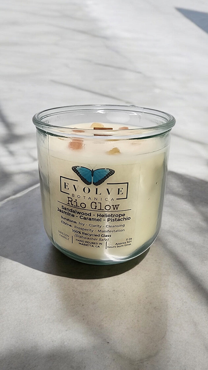 Evolve Botanica Rocks Candle Rio Glow with sunstone and citrine gemstones, soy wax, and wood wick, glowing softly.