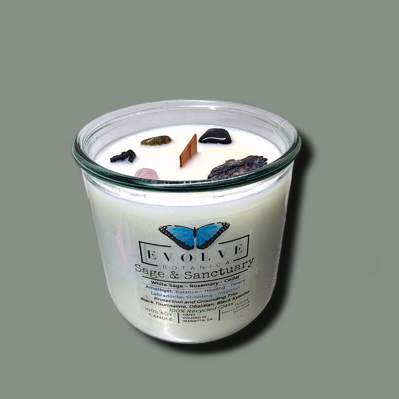 Evolve Botanica Rocks Candle Sage & Sanctuary with black kyanite, tourmaline, obsidian, amethyst, and labradorite crystals.