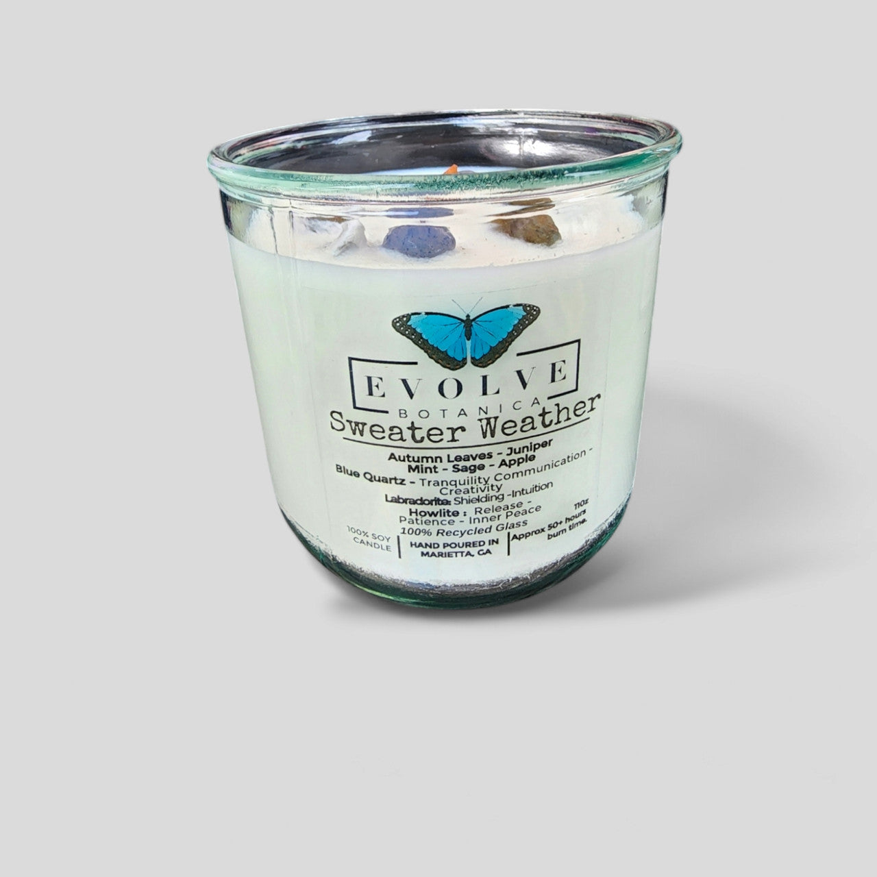 Evolve Botanica Rocks Candle Sweater Weather with wood wick, Howlite, Labradorite, Sodalite, and soy wax in a cozy setting.