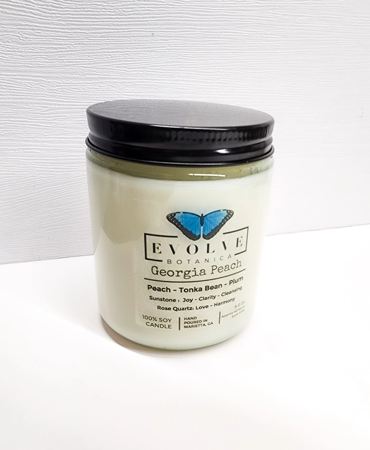 Evolve Botanica 9oz jam jar soy candle with Georgia Peach scent, featuring sunstone and rose quartz crystals, natural wood wick