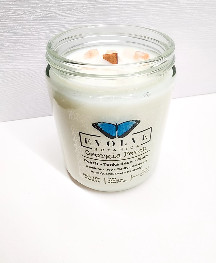 Evolve Botanica 9oz jam jar soy candle with Georgia Peach scent, sunstone, and rose quartz crystals, natural wood wick.