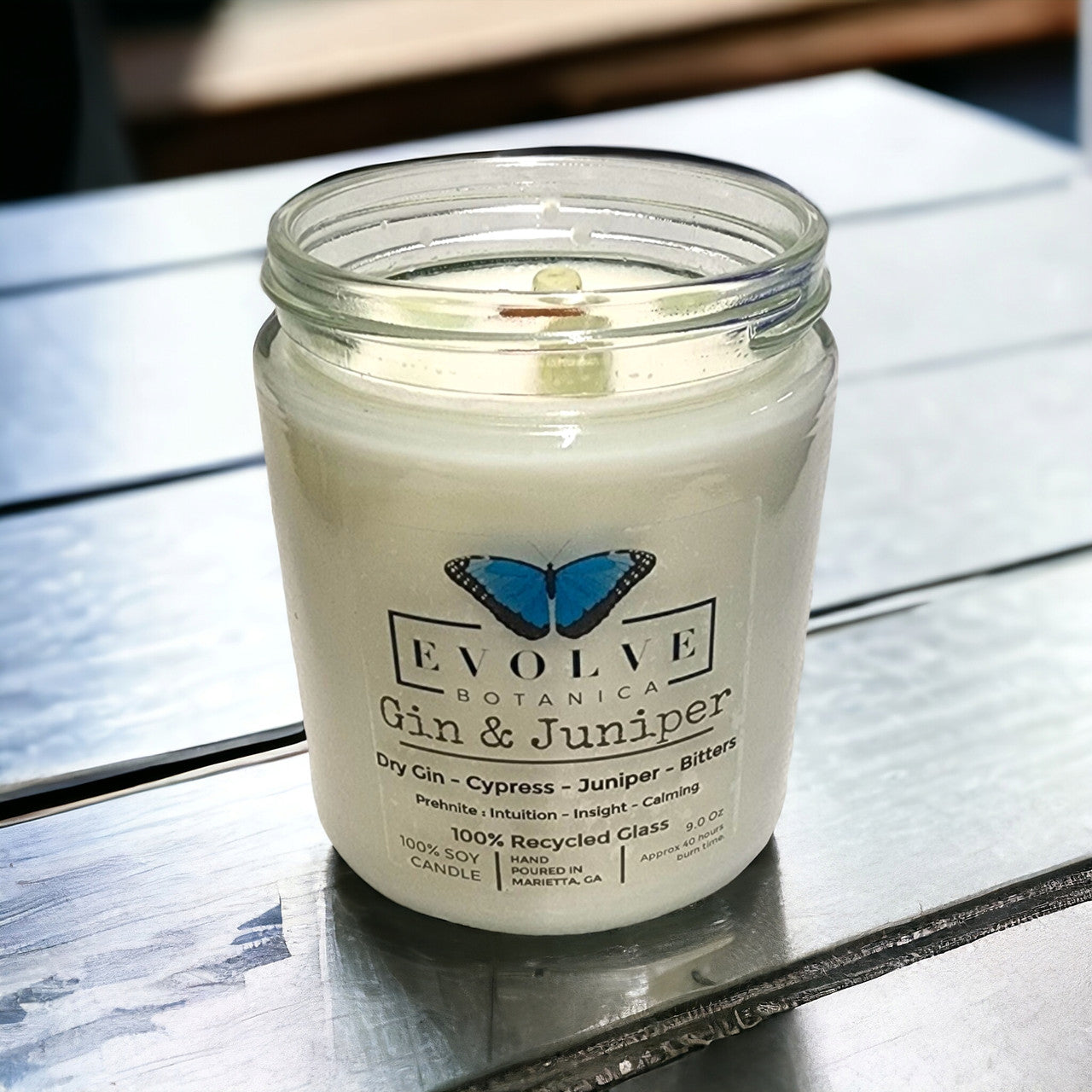 Evolve Botanica 9oz jam jar soy candle with gin & juniper scent, natural wood wick, featuring prehnite crystal accents.