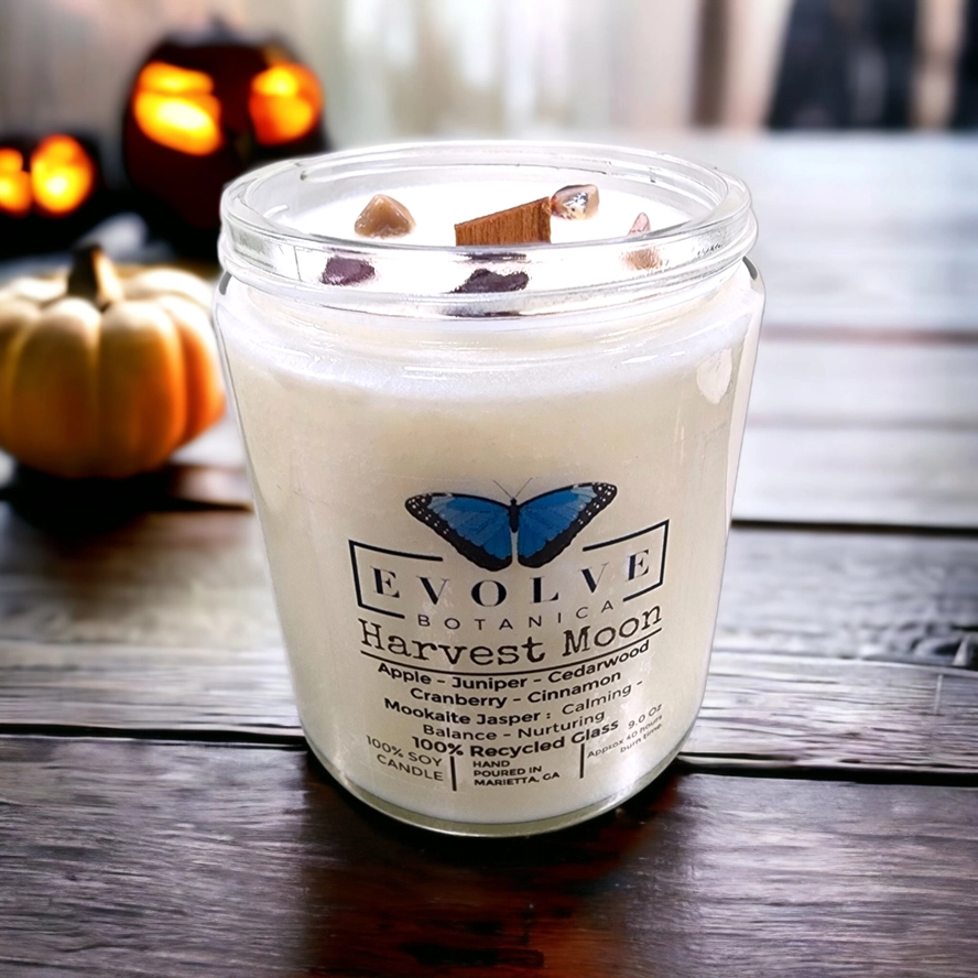 Evolve Botanica 9oz jam jar soy candle with harvest moon scent and mookite crystal, featuring natural wood wick for cozy ambiance.
