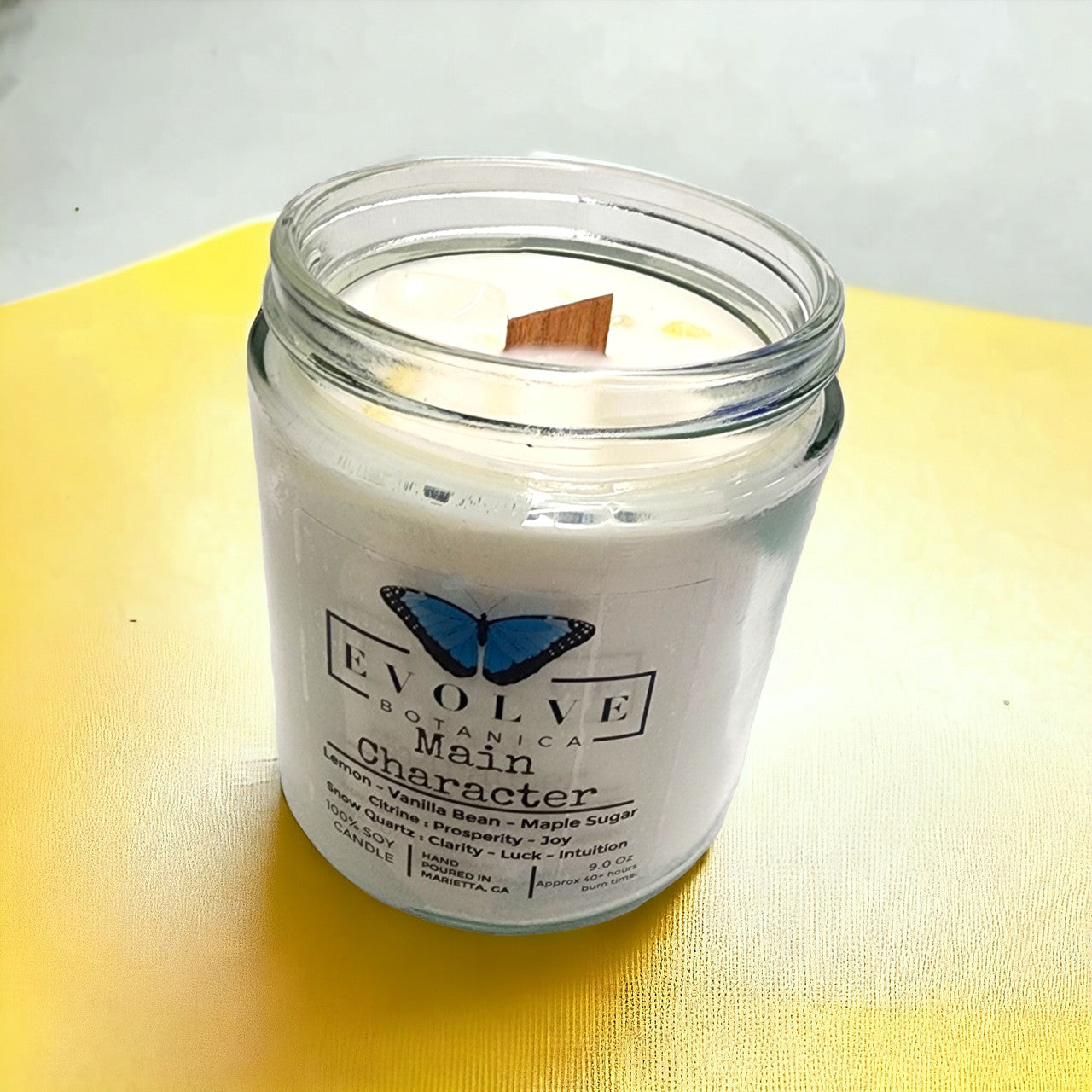 Evolve Botanica Classic 9oz jam jar soy candle with citrine and snow quartz crystals, natural wood wick, and crystal accents.