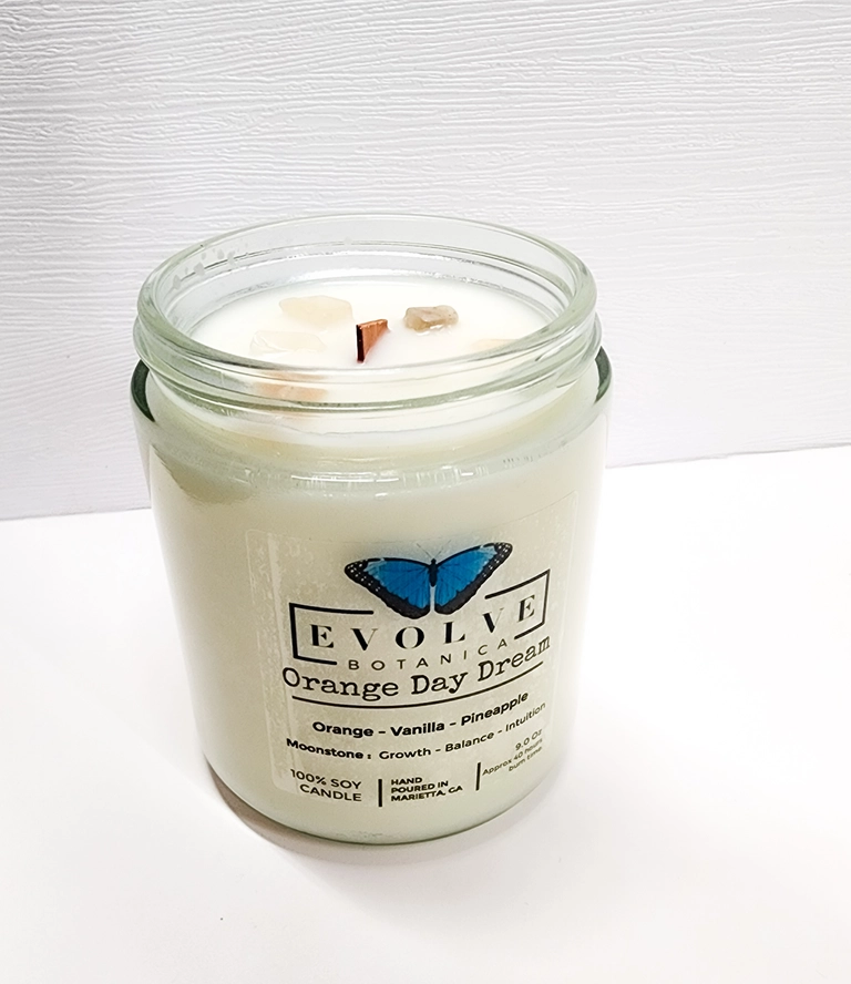Evolve Botanica 9oz jam jar crystal soy candle with orange daydream scent and natural wood wick in Moonstone color.