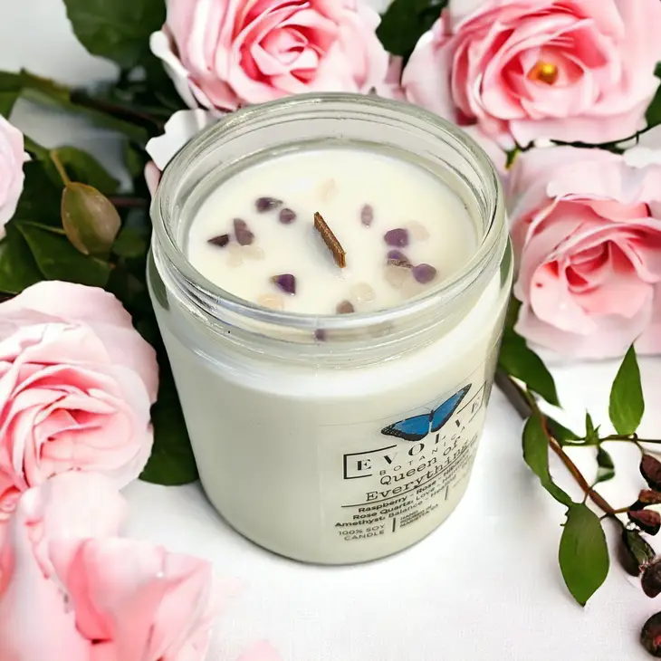 Evolve Botanica 9oz jam jar soy candle labeled Queen of Everything with rose quartz and amethyst crystals, natural wood wick.