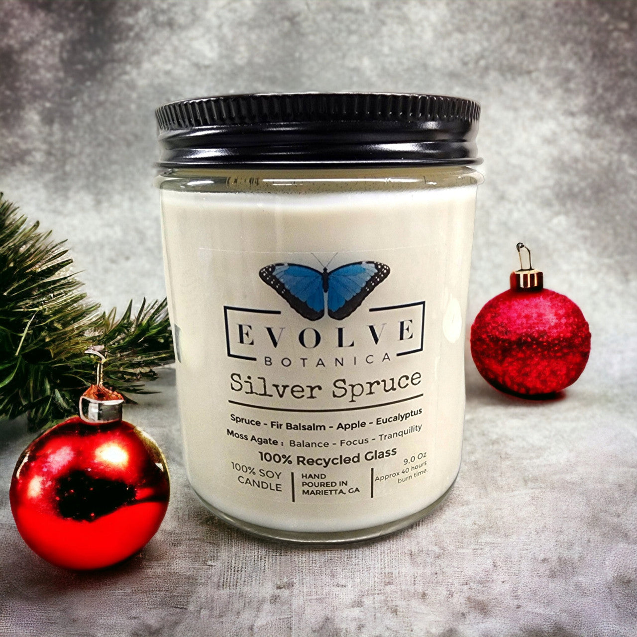 Classic 9oz Jam Jar soy candle by Evolve Botanica with Silver Spruce scent, moss agate accent, natural wood wick, and crystal decoration.