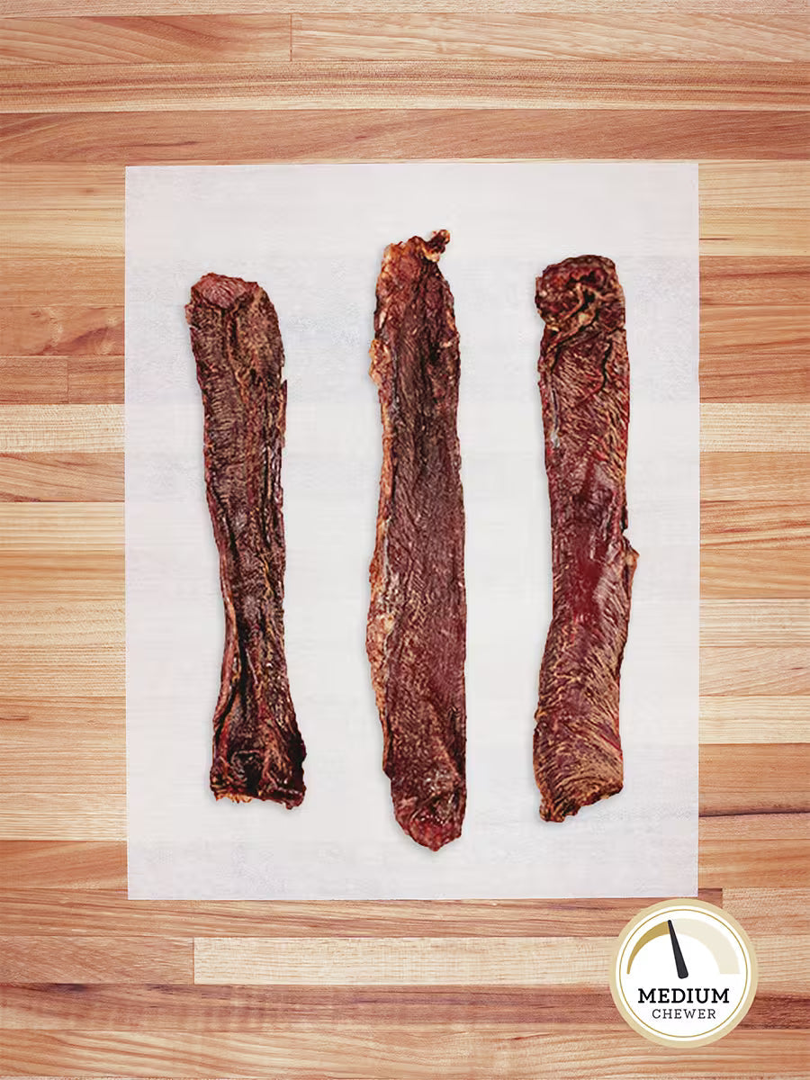 Three Farm Hounds Beef Weasand (esophagus) chews, made from pasture-raised cattle, are lined up on parchment atop a wooden surface. A circular badge in the corner indicates they are for Medium Chewers.