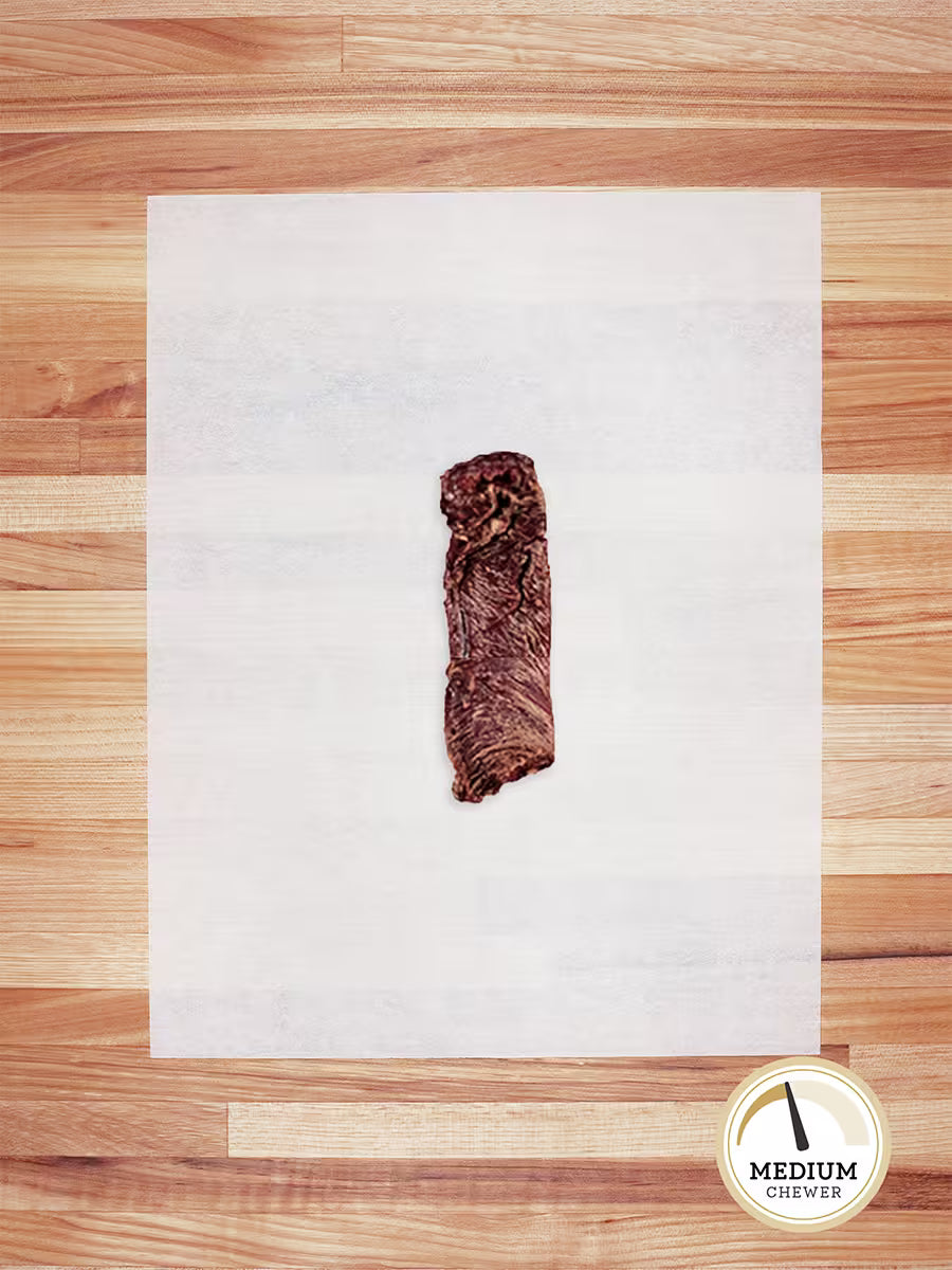 A single strip of Farm Hounds Beef Weasand - Esophagus from pasture-raised cattle rests on a white sheet on wood, with a round Medium Chewer label in the bottom right corner.