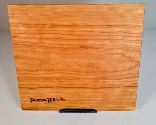 Cherrywood cutting board by Farmer Bill's Provisions, made and sourced in the USA, shown with a smooth natural wood surface.