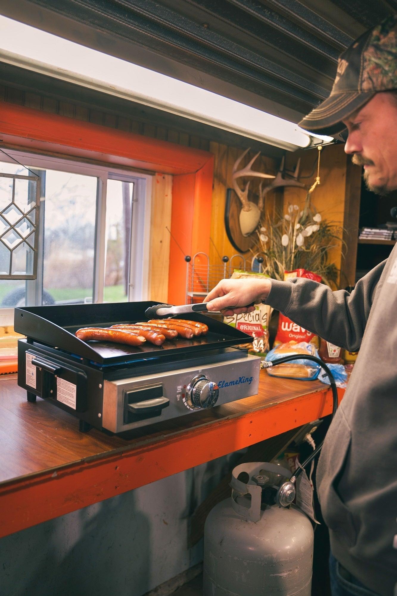 Flame King flat-top portable propane cast iron grill and griddle for camping, with a sturdy design and cooking surface.