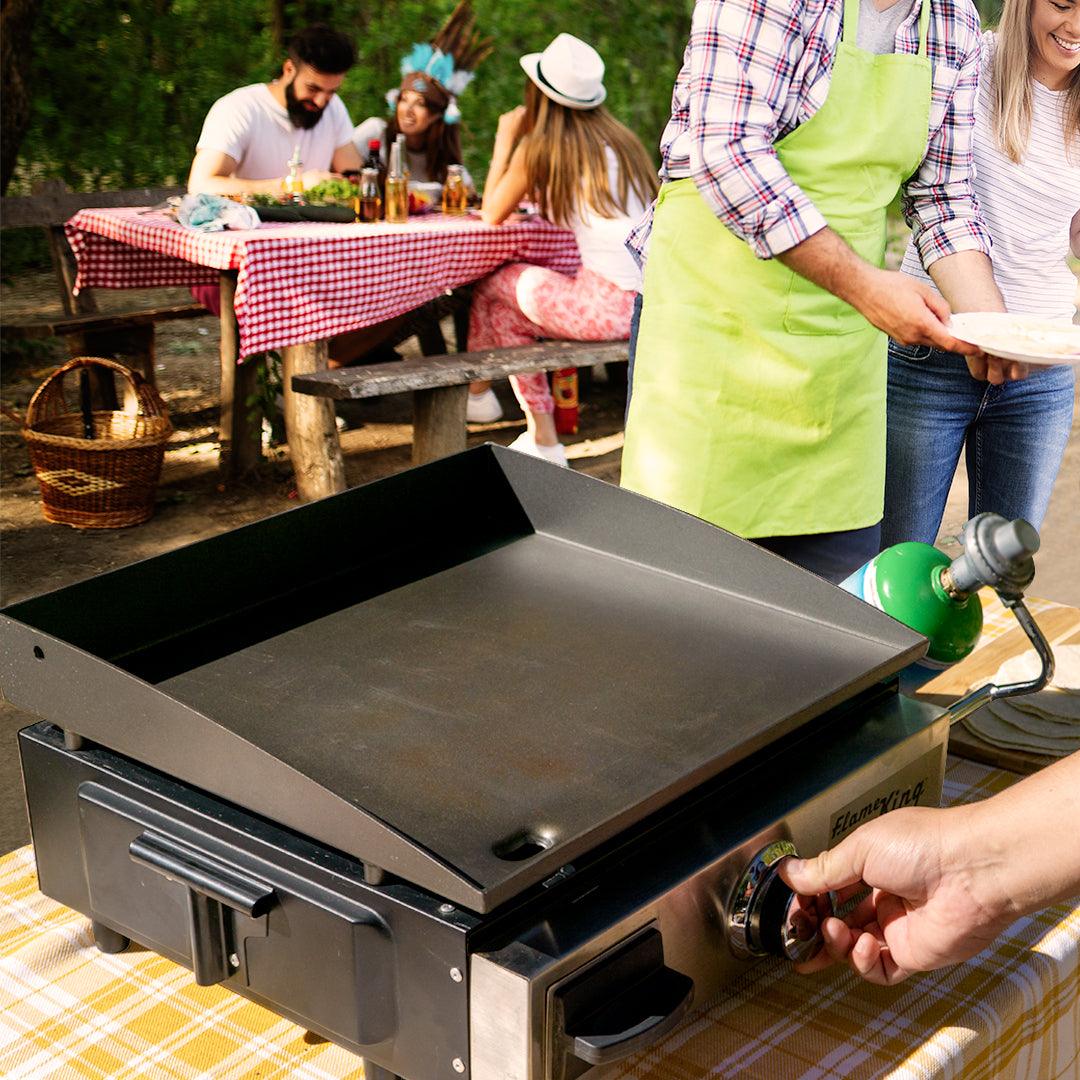 Portable Flame King cast iron flat top propane grill griddle for camping, shown with cooking surface and control knobs.
