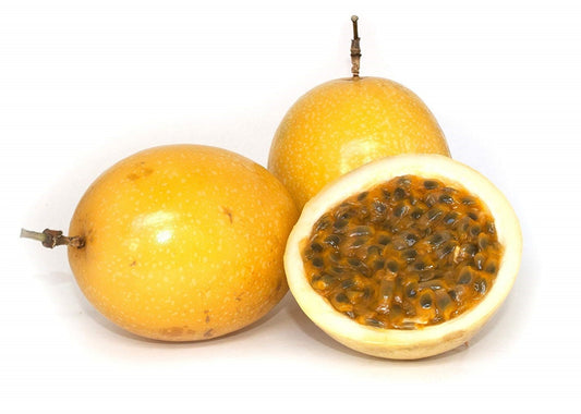 Yellow passion fruit from Florida Plants Nursery with vibrant yellow skin and green leaves in a lush garden setting.