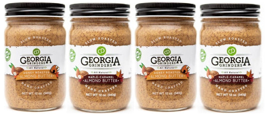 Four jars of Georgia Grinders Maple Caramel Almond Butter and Honey Roasted Almond Butter Mix Pack (two 12oz jars each) are shown side by side with black lids; the image is distorted with diagonal white lines.