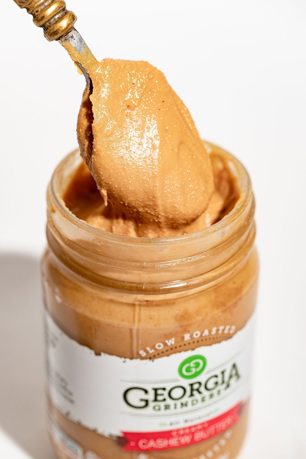 A spoon scooping creamy Georgia Grinders Cashew Butter from the 12 oz WHOLE30 Nut Butter Assortment 4 Pack—your ideal pick for delicious, Whole30-approved nut butters.