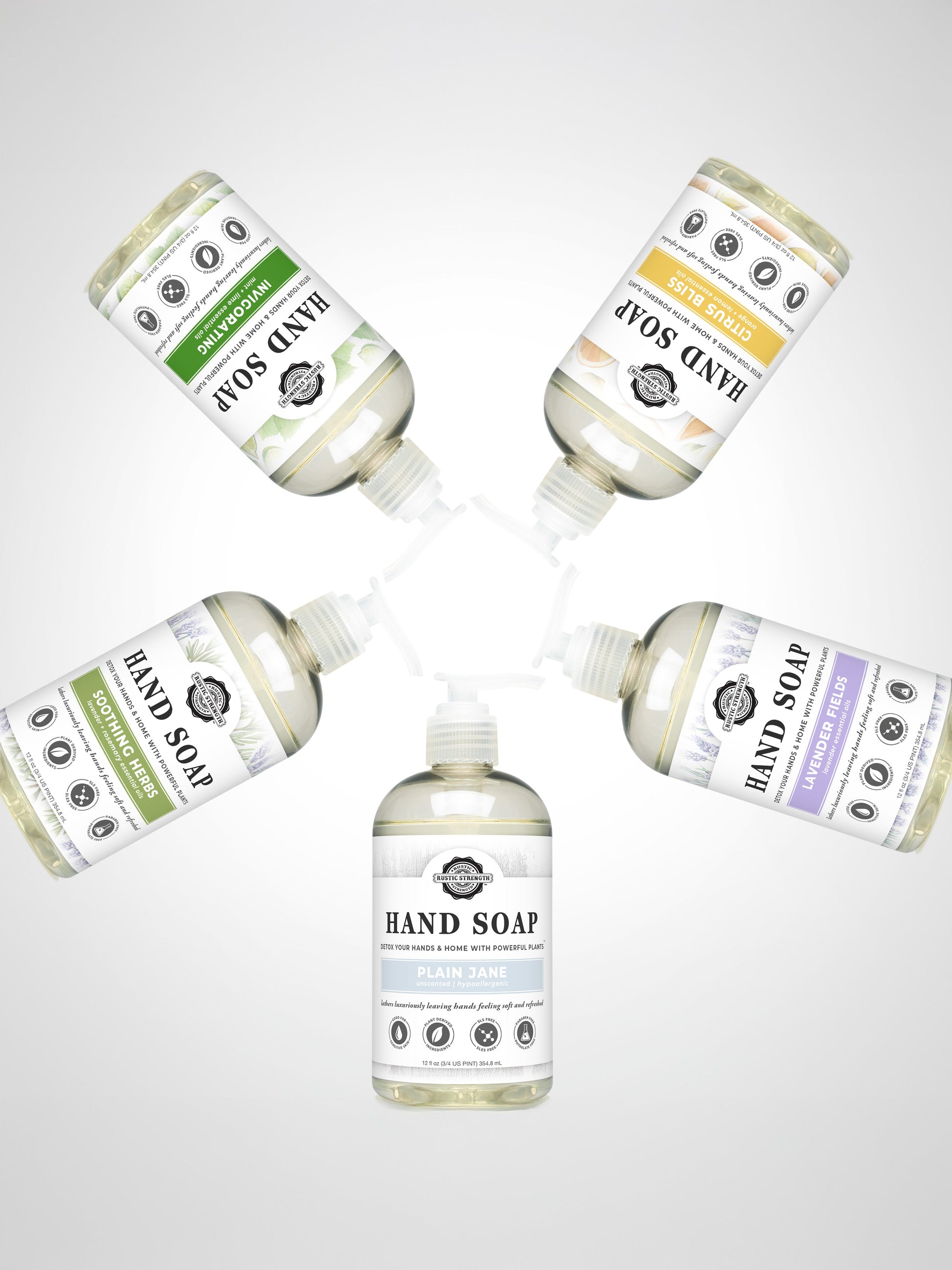 Five bottles of Rustic Strength Hand Soap, including the Lavender Fields scent, are arranged in a circle with pumps facing inward. Each has a distinct colored label on a white background and includes biodegradable options.