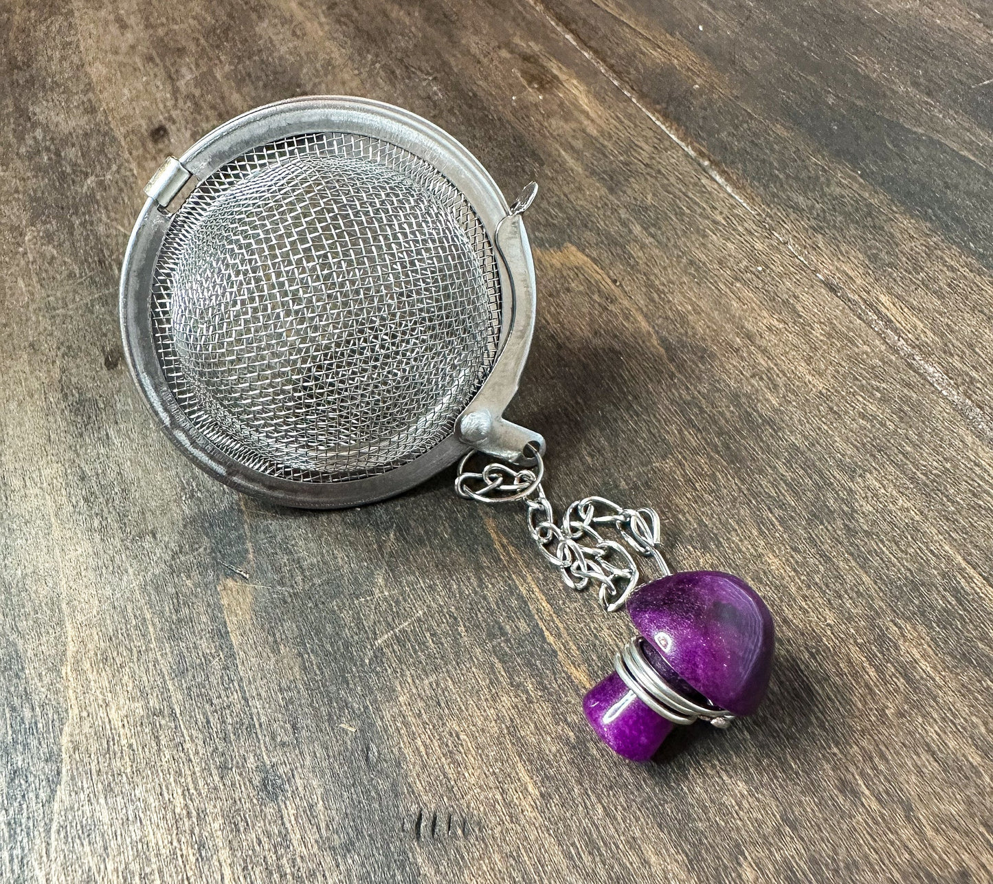 Herbalroseapothecary tea ball infuser with stainless steel mesh for brewing loose leaf tea in a cup or teapot.