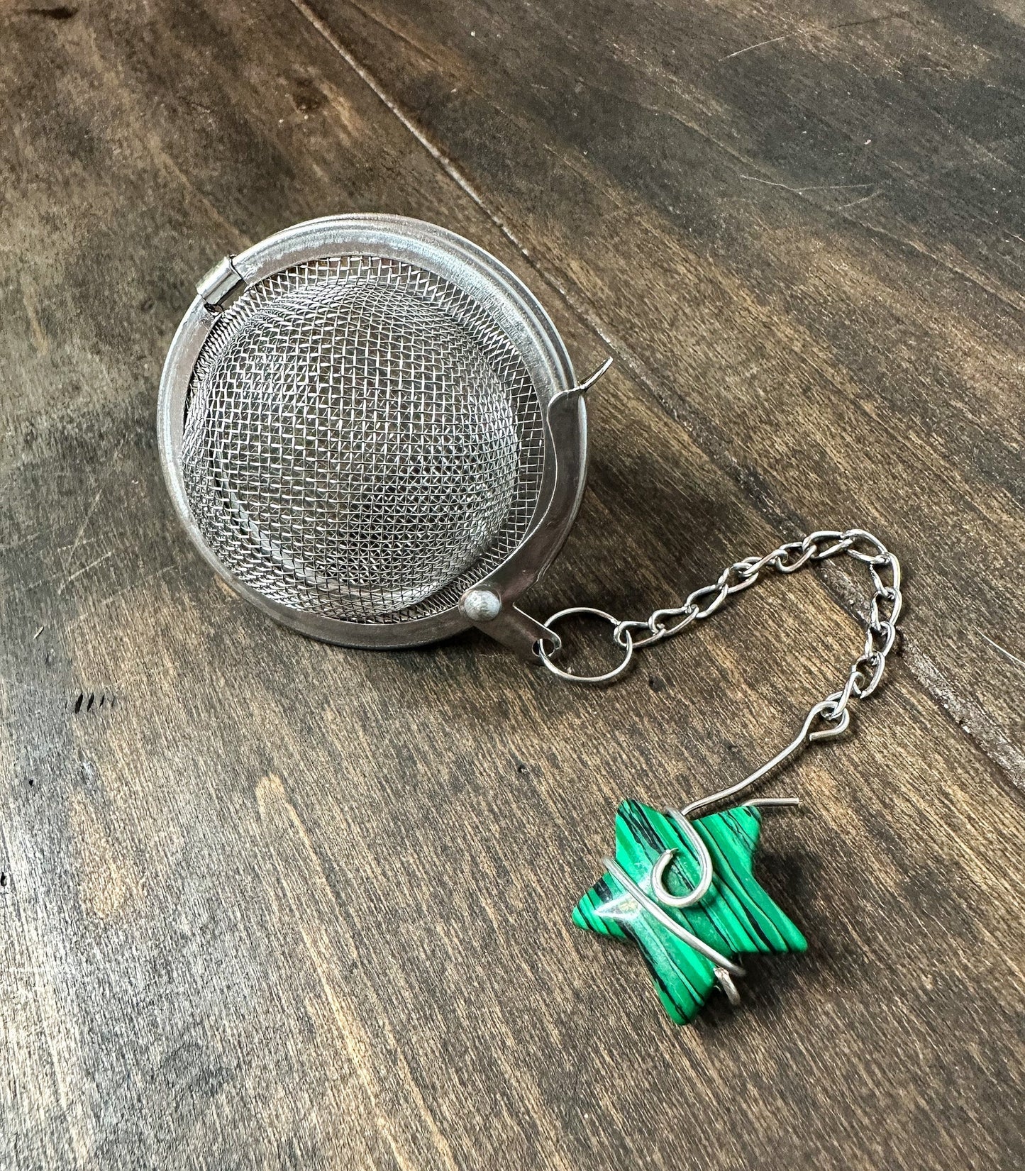 Herbalroseapothecary tea ball infuser with stainless steel mesh and handle for brewing loose leaf tea.