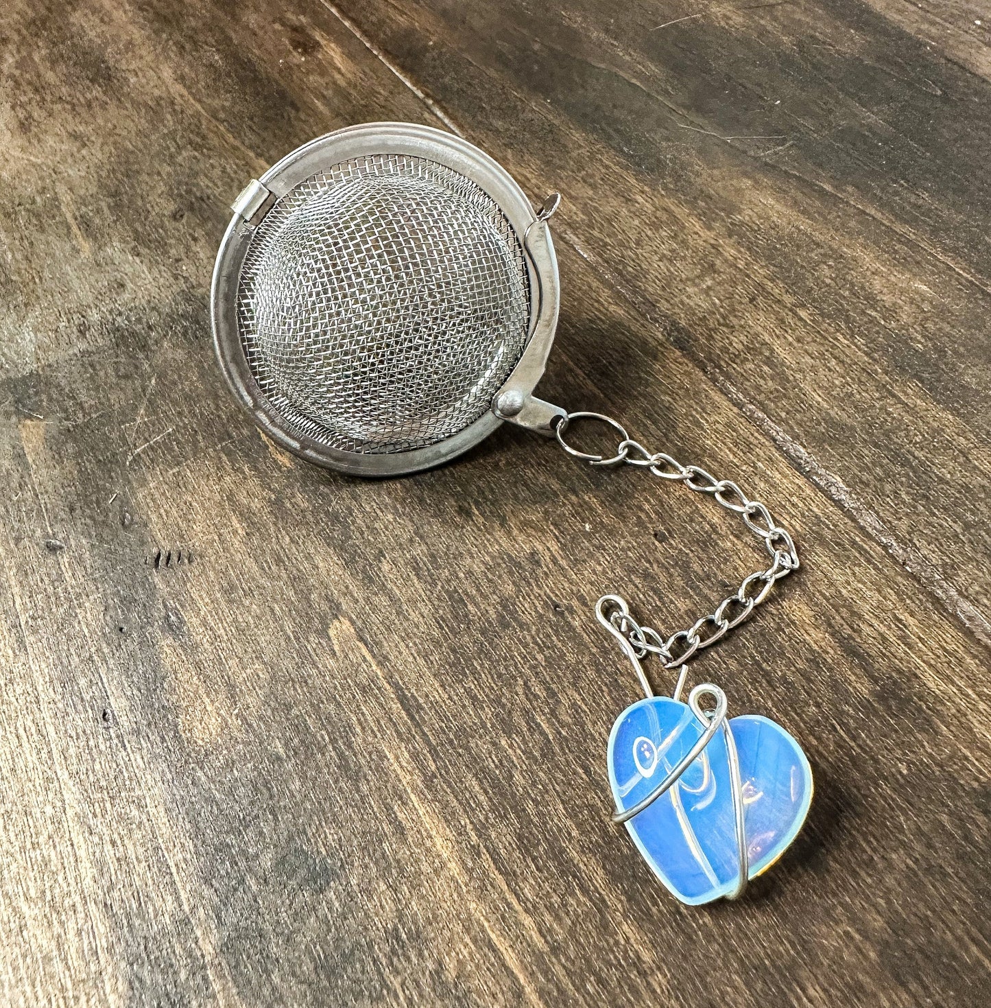 Herbalroseapothecary tea ball infuser with stainless steel mesh for loose leaf tea brewing in a teapot or cup.