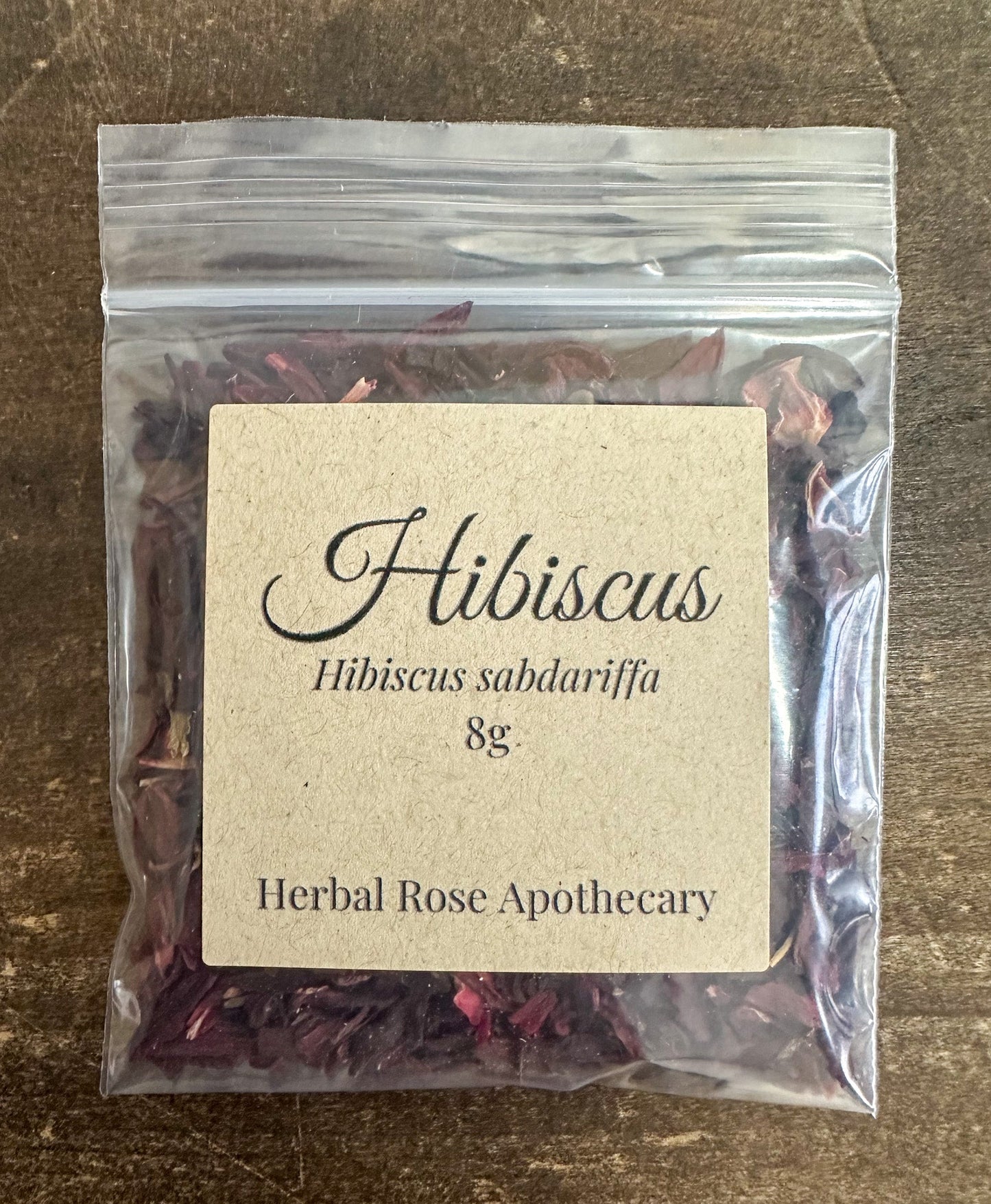 Dried hibiscus herbs in an 8g package from HerbalRoseApothecary, showing vibrant red dried flower petals.