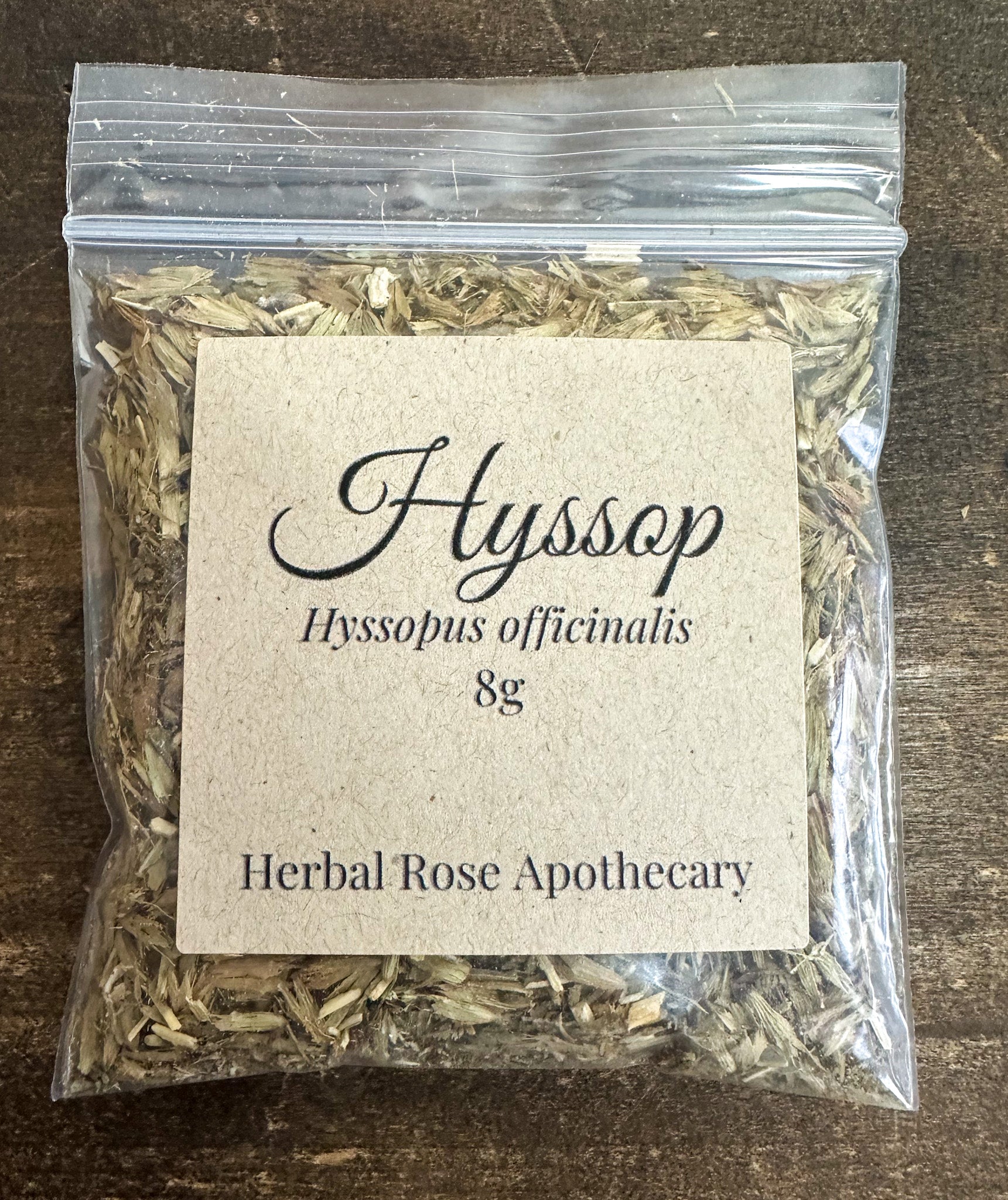 Dried hyssop herbs in an 8g package from Herbal Rose Apothecary, showing fresh green leaves and stems.