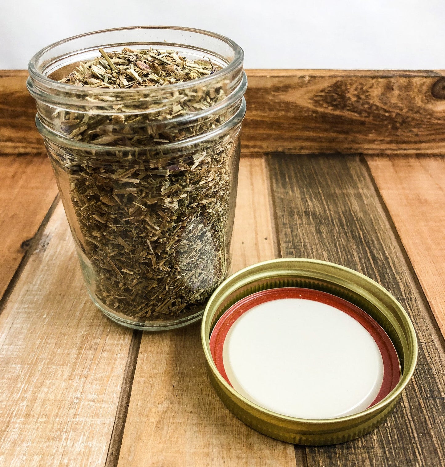 Small white and wood-colored glass jars of dried hyssop herbs from HerbalRoseApothecary, with labels on each jar.
