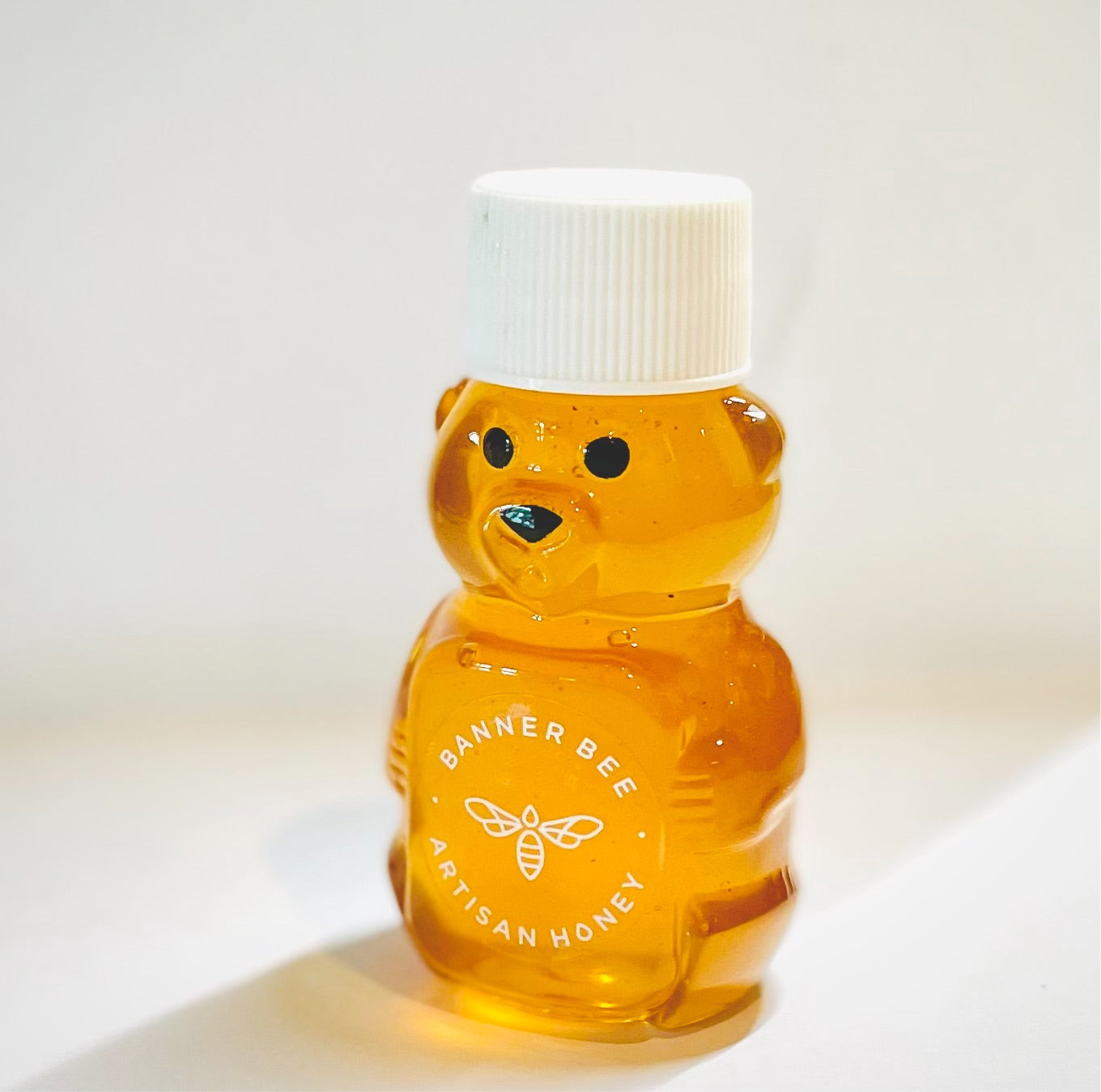 Mini honey bear container filled with raw honey from BannerBee Company LLC, showcasing a cute bear-shaped honey dispenser.