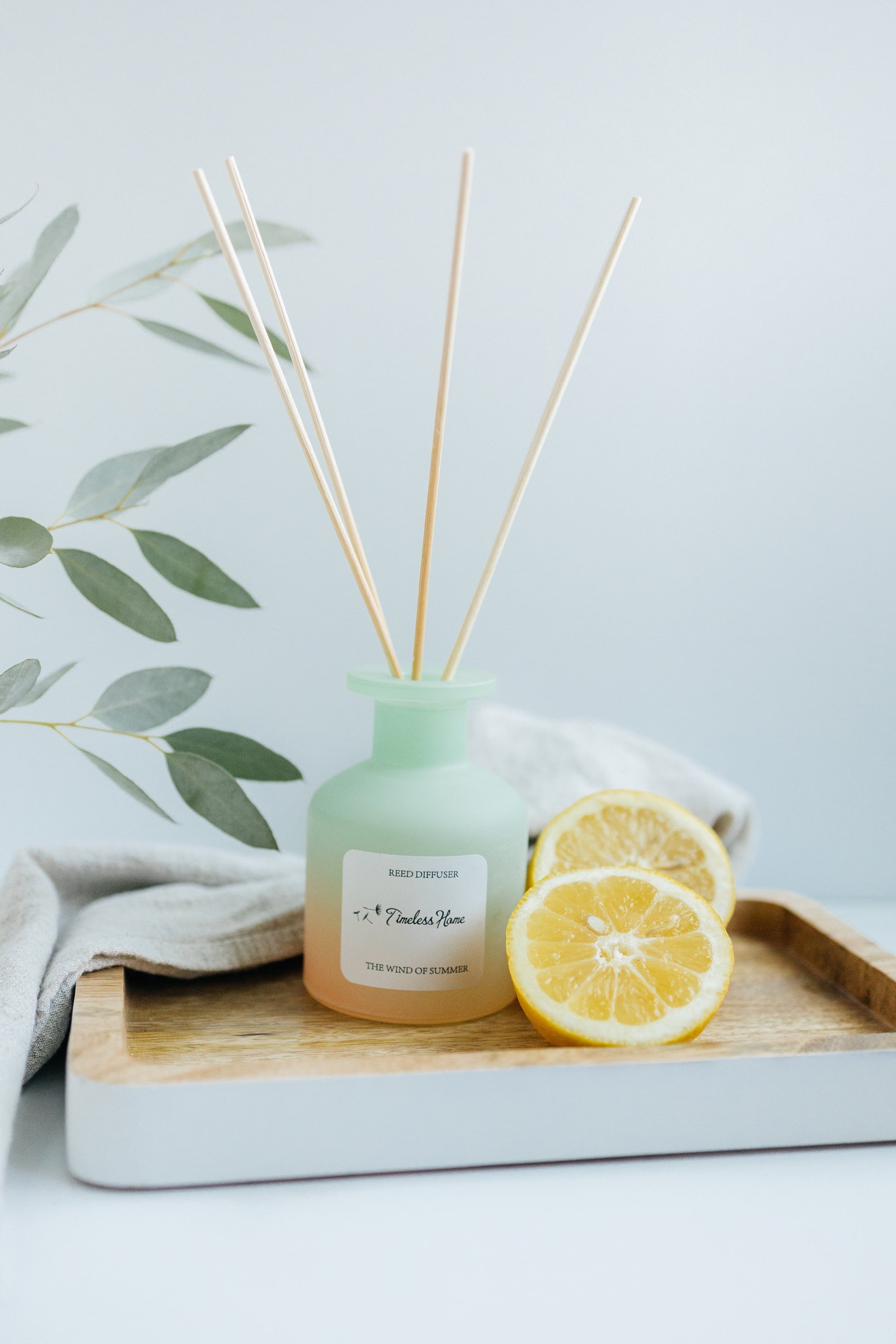 Reed diffuser labeled "The Wind of Summer" by Timeless Organics Skin Care, featuring elegant glass bottle and natural reed sticks.
