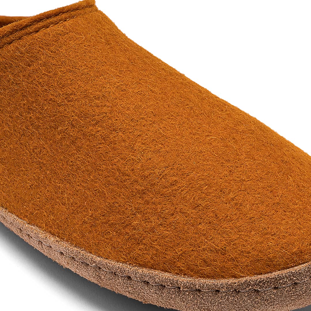 Close-up of a Kyrgies Indoor Wool Slide by Kyrgies, featuring an orange-brown handcrafted wool upper with a textured surface and a light brown sole, displayed against a white background.