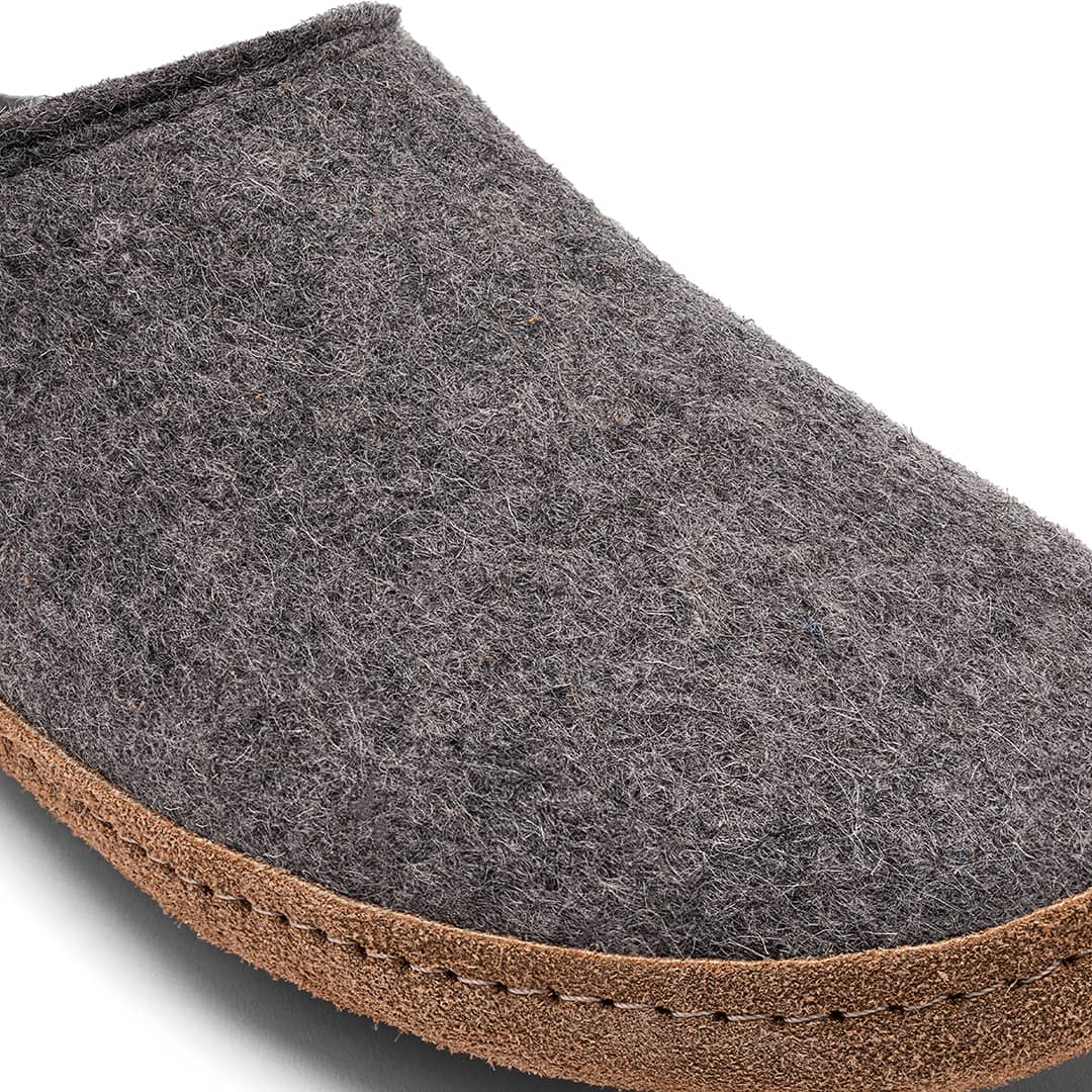 Close-up of Kyrgies Indoor Wool Slides, handcrafted gray wool slippers with brown textured stitching around the sole—these biodegradable Kyrgies slippers are shown on a white background.