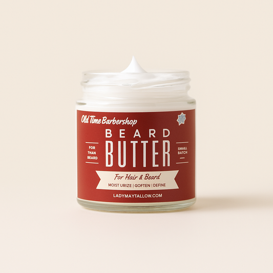 A glass jar of Lady May Tallow Old Time Barbershop Natural Tallow Beard & Body Butter for Men, filled with white cream, sits against a plain background. This all-natural formula conditions, softens, and defines hair and beards.