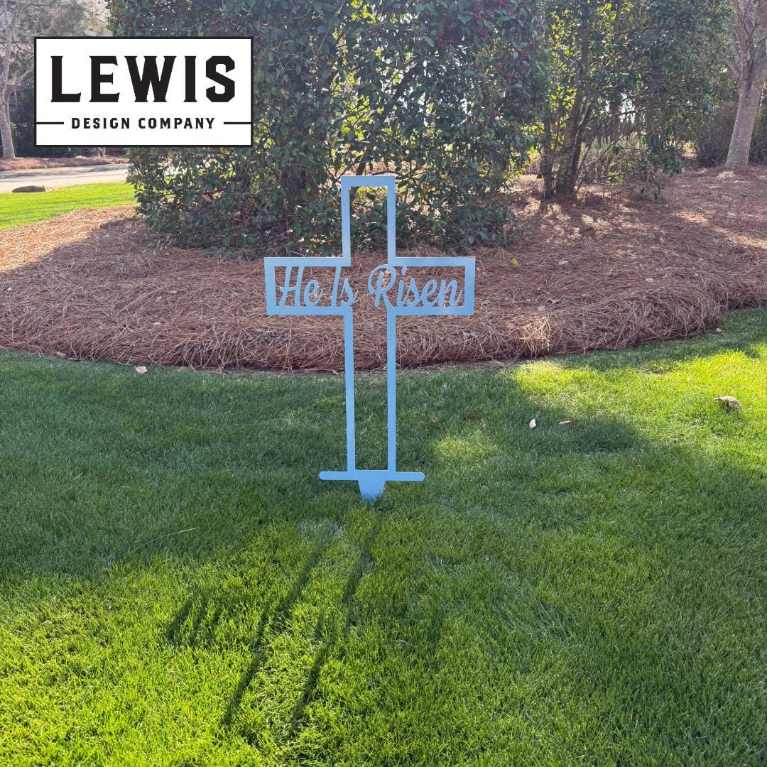 Pastel blue He Is Risen Cross metal garden sign by Lewis Design Company, outdoor patio and Easter yard art, 8x4 inches