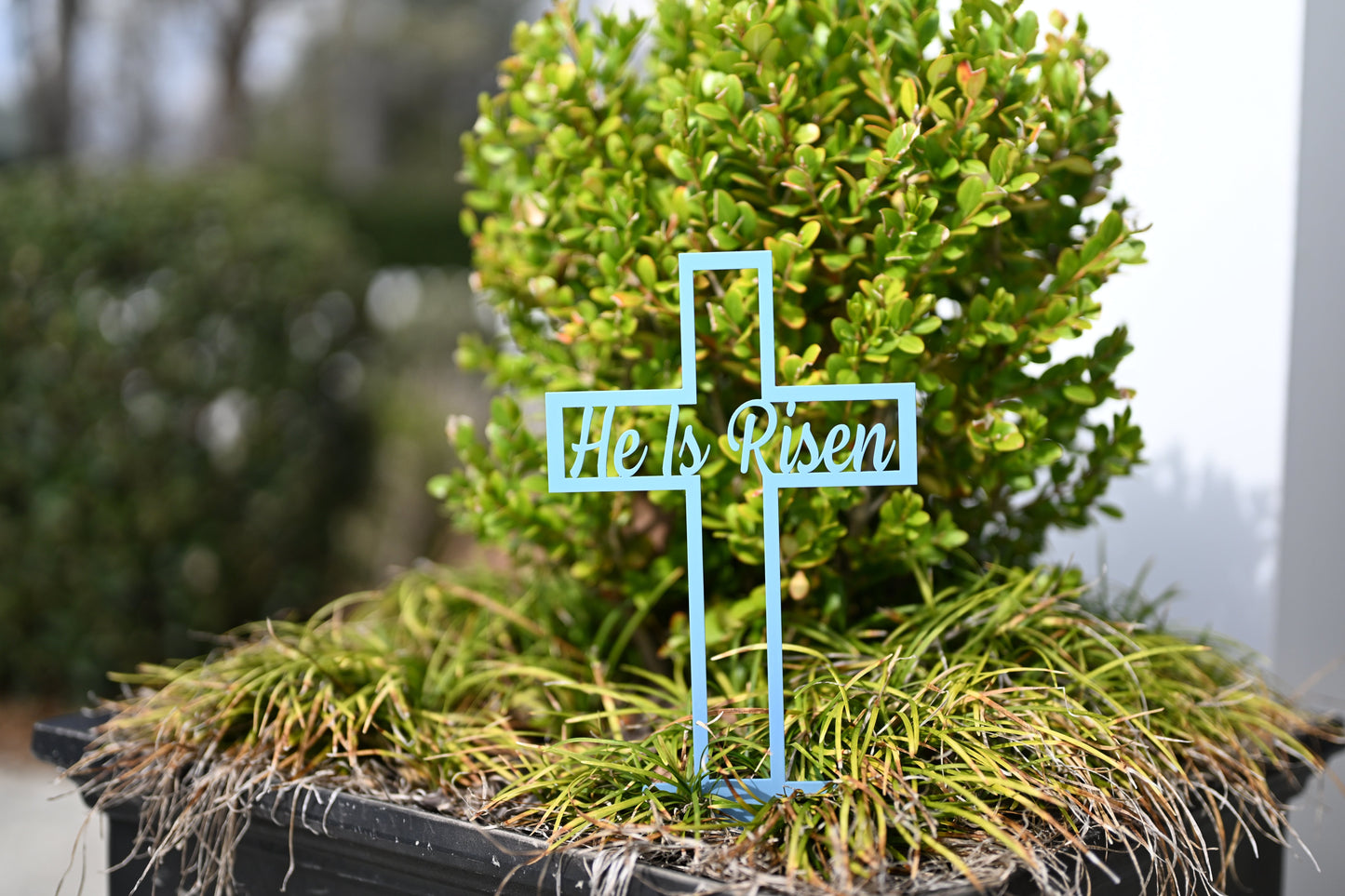 Pastel blue He Is Risen Cross metal garden sign by Lewis Design Company, outdoor Easter yard and patio garden art.