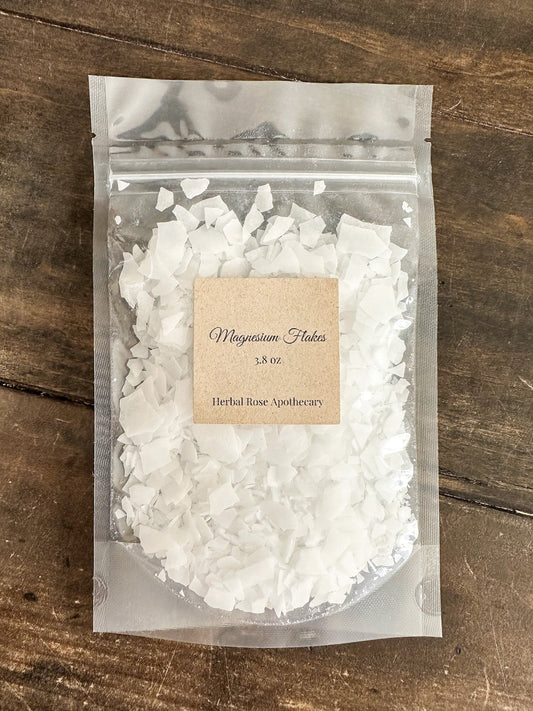 HerbalRoseApothecary magnesium flakes labeled front for bath salts and oats, showing the natural mineral flakes in a clear container.