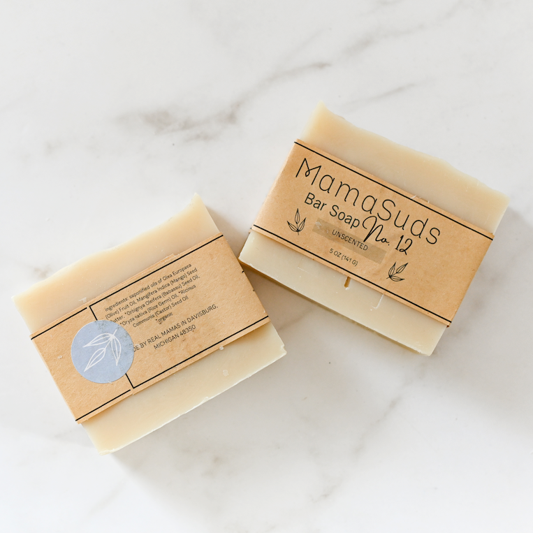 Two rectangular bars of MamaSuds Unscented No. 12 Bar Soap with brown paper labels sit on white marble, appearing handcrafted and natural, and made with certified organic ingredients.