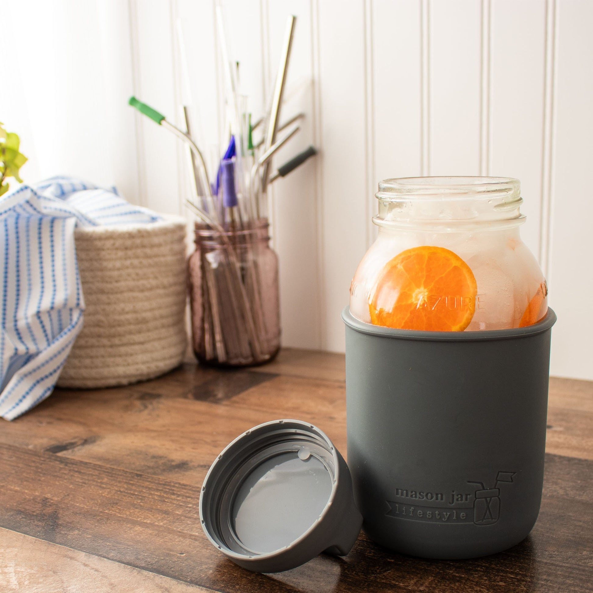 Mason Jar Lifestyle 32oz glass water bottle with blue silicone sleeve, carry handle, and lid on a white background.