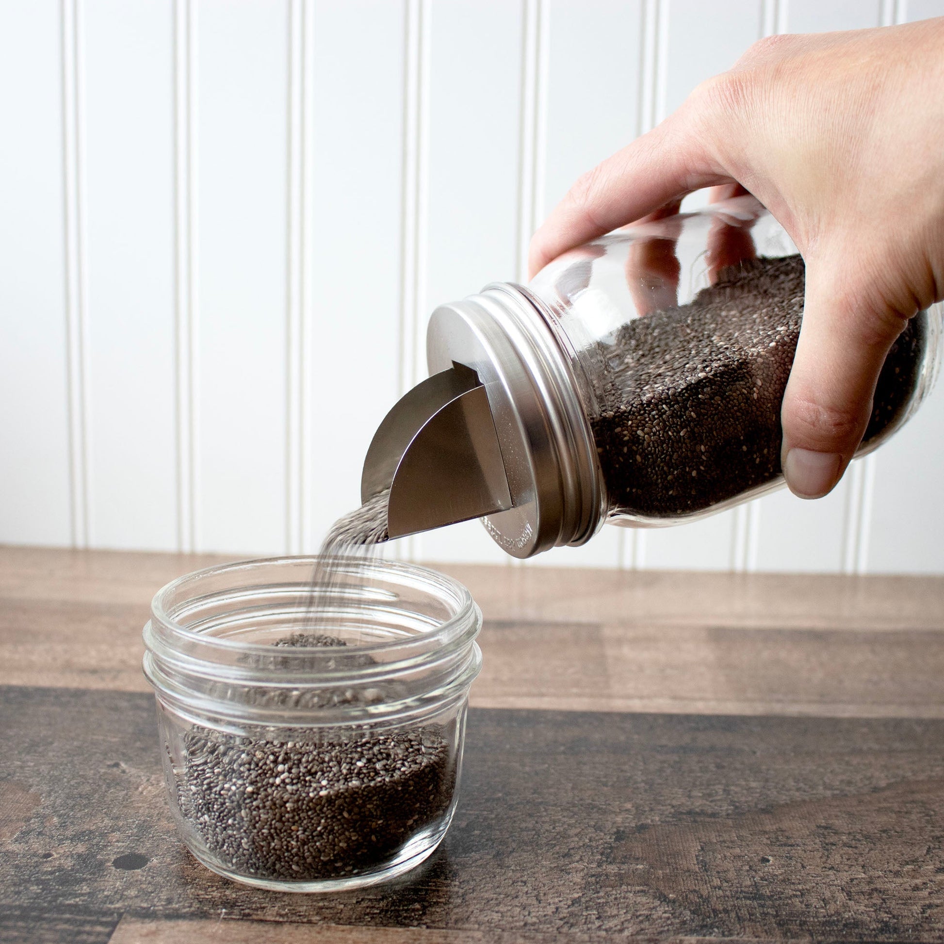 Two stainless steel grain dispenser lids for regular-mouth Mason jars, designed for easy pouring and storage.