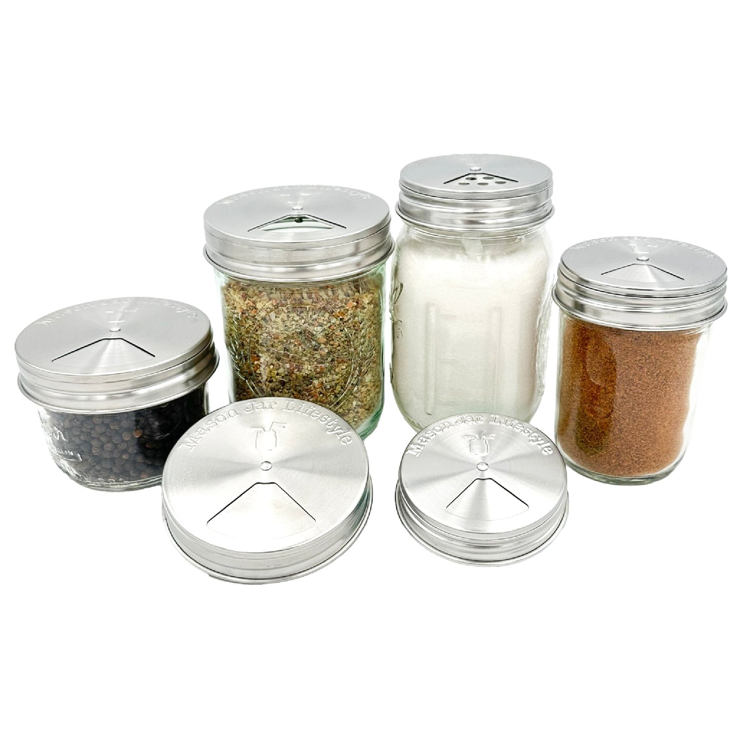Four Mason Jar Lifestyle Spice Shakers with stainless steel lids are displayed on a white background. Each jar has an adjustable shaker-style top and suits mason jars, ideal for storing various spices or seasonings.