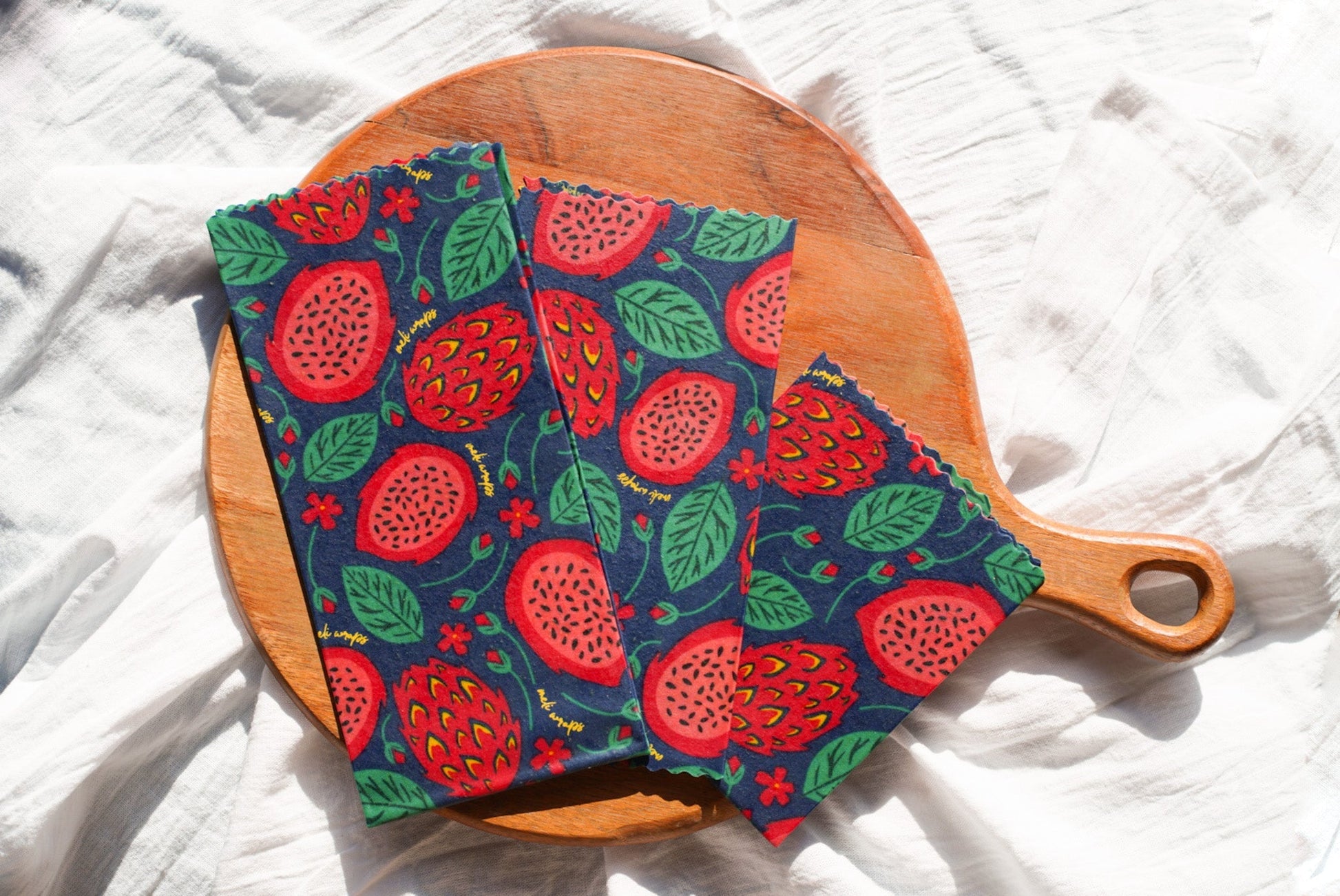 Set of three Meli Wraps beeswax food wraps with vibrant dragonfruit print in small, medium, and large sizes.