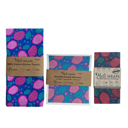 The Meli Wraps Beeswax Eco-Friendly Dragonfruit Gift Set features vibrant fruit and leaf designs in pink, purple, blue, and green on eco-friendly kitchen towels, Swedish dishcloths, and beeswax wraps displayed side by side.