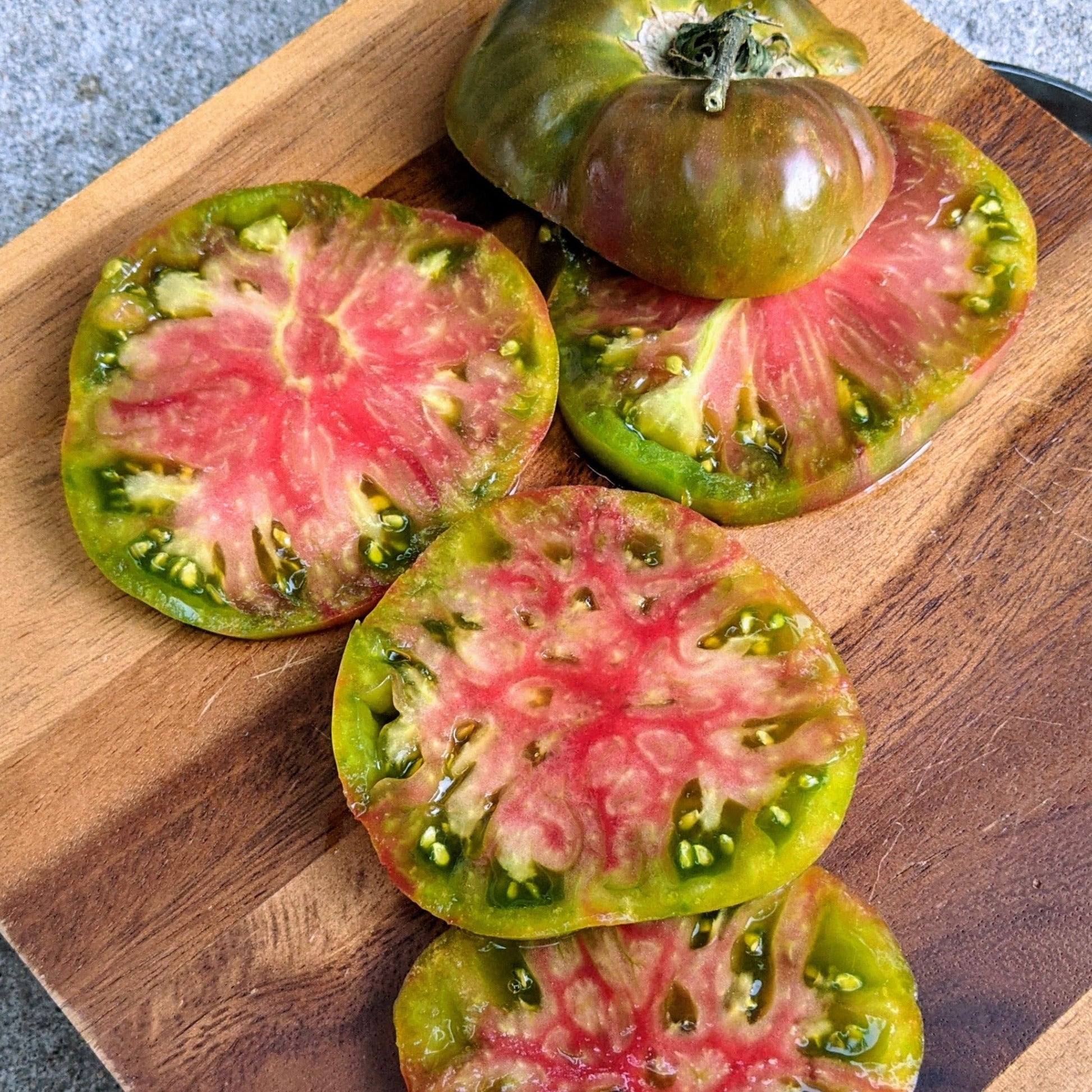 Black Ananas Noire tomato from MIgardener, showing ripe, dark purple and black heirloom tomatoes on the vine.