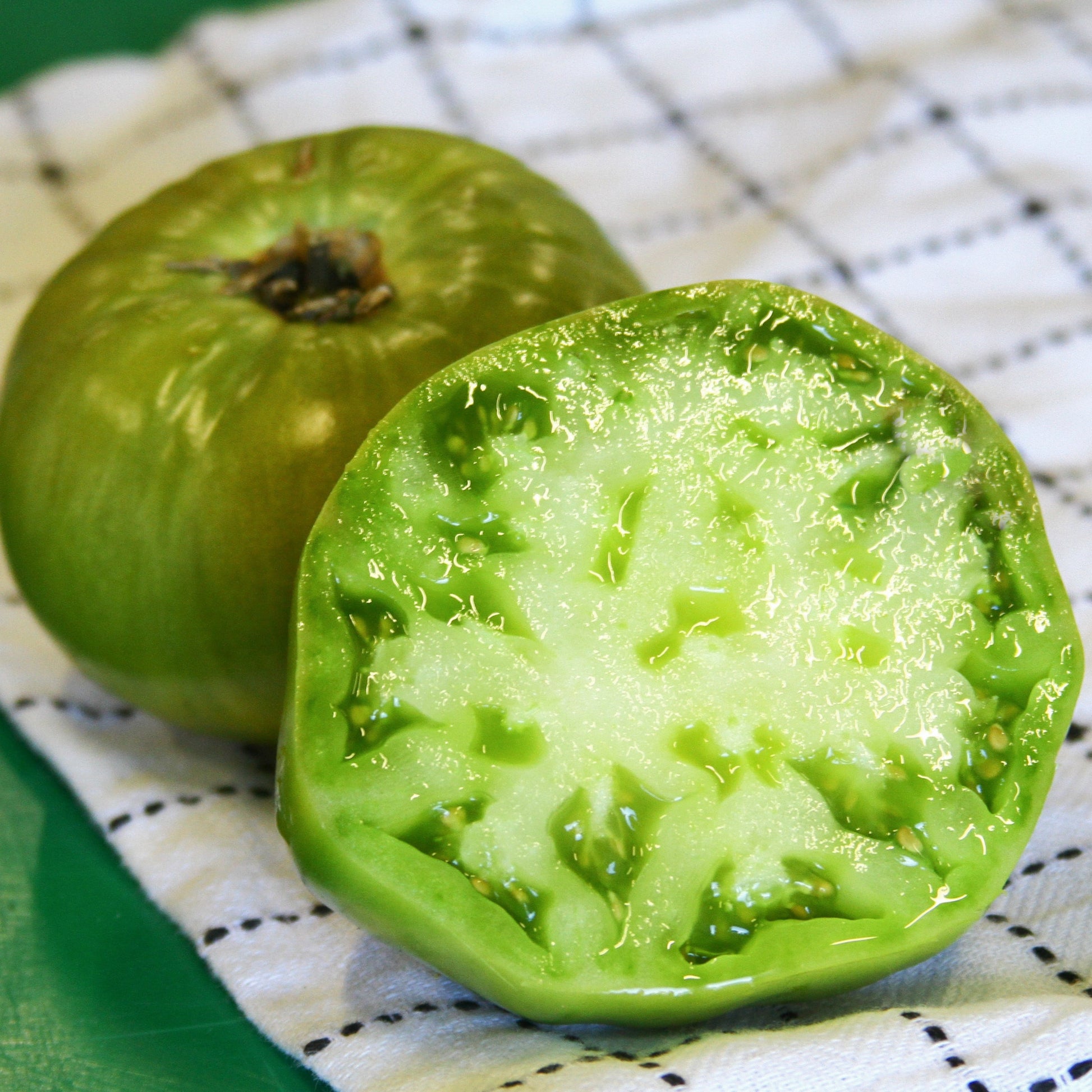 Fresh Aunt Ruby's German Green Tomato from MIgardener, showcasing its vibrant green color and ripe, plump appearance.
