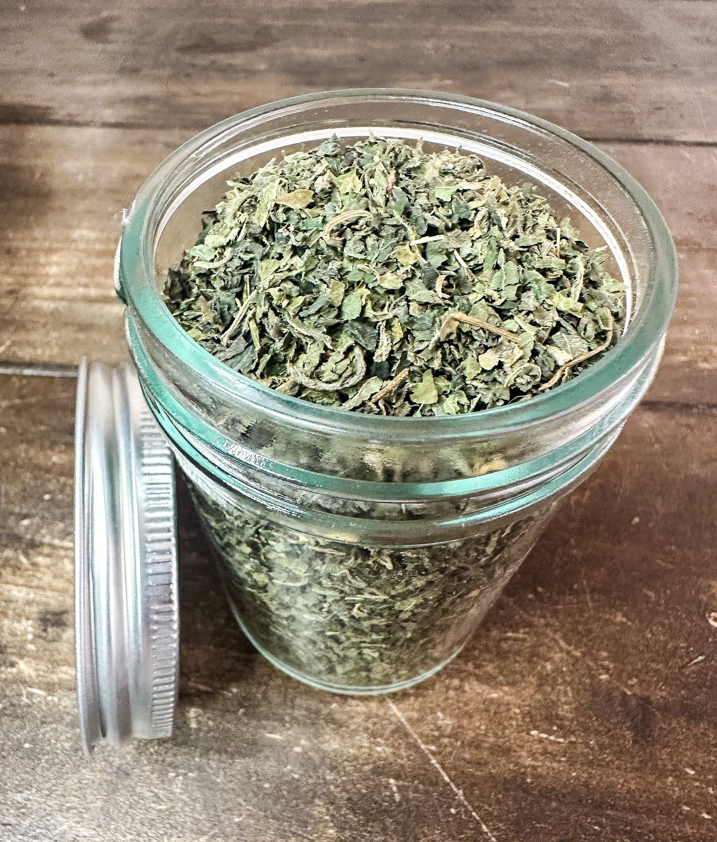 Small jar of dried nettle herbs in a herbalroseapothecary herb jar, showcasing dried green nettle leaves.