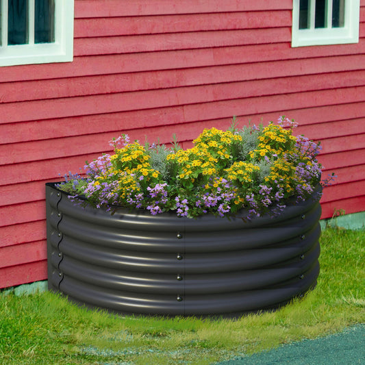 An Olle Gardens 17" Tall Decorative Semi-circle Raised Garden Bed by Ollegardens, filled with yellow and purple flowers, sits beside a red wooden building with white-trimmed windows, surrounded by grass and a small gravel path.