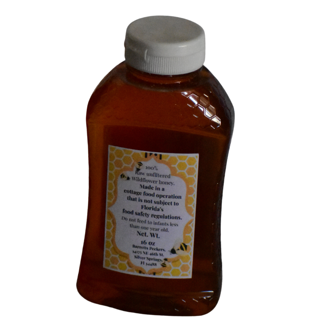 Raw wildflower honey from Ocala National Forest in a clear jar, showcasing golden, unfiltered honey on a white background.