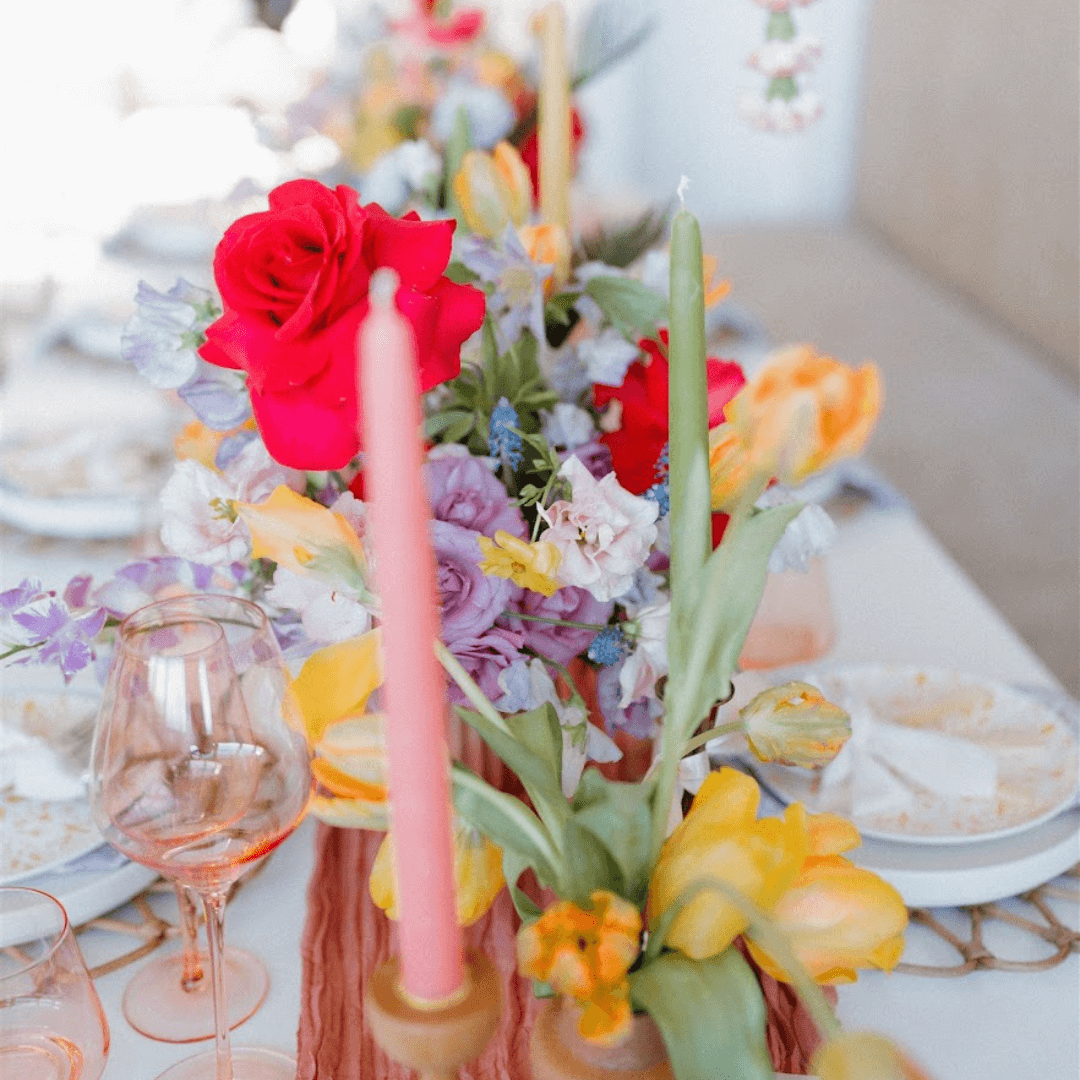 Bluecorn Candles spring beeswax taper candles in dusty rose, apricot, pistachio, and raw green colors, arranged for a boho wedding.
