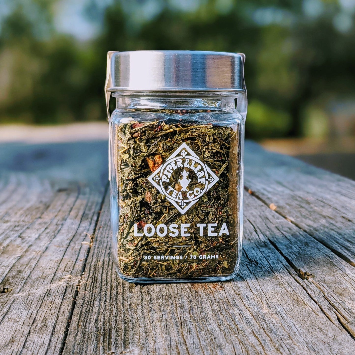 Glass jar of Piper and Leaf Tea Co. Sassyfras Strawberry loose leaf tea with vibrant red and green tea leaves visible inside.