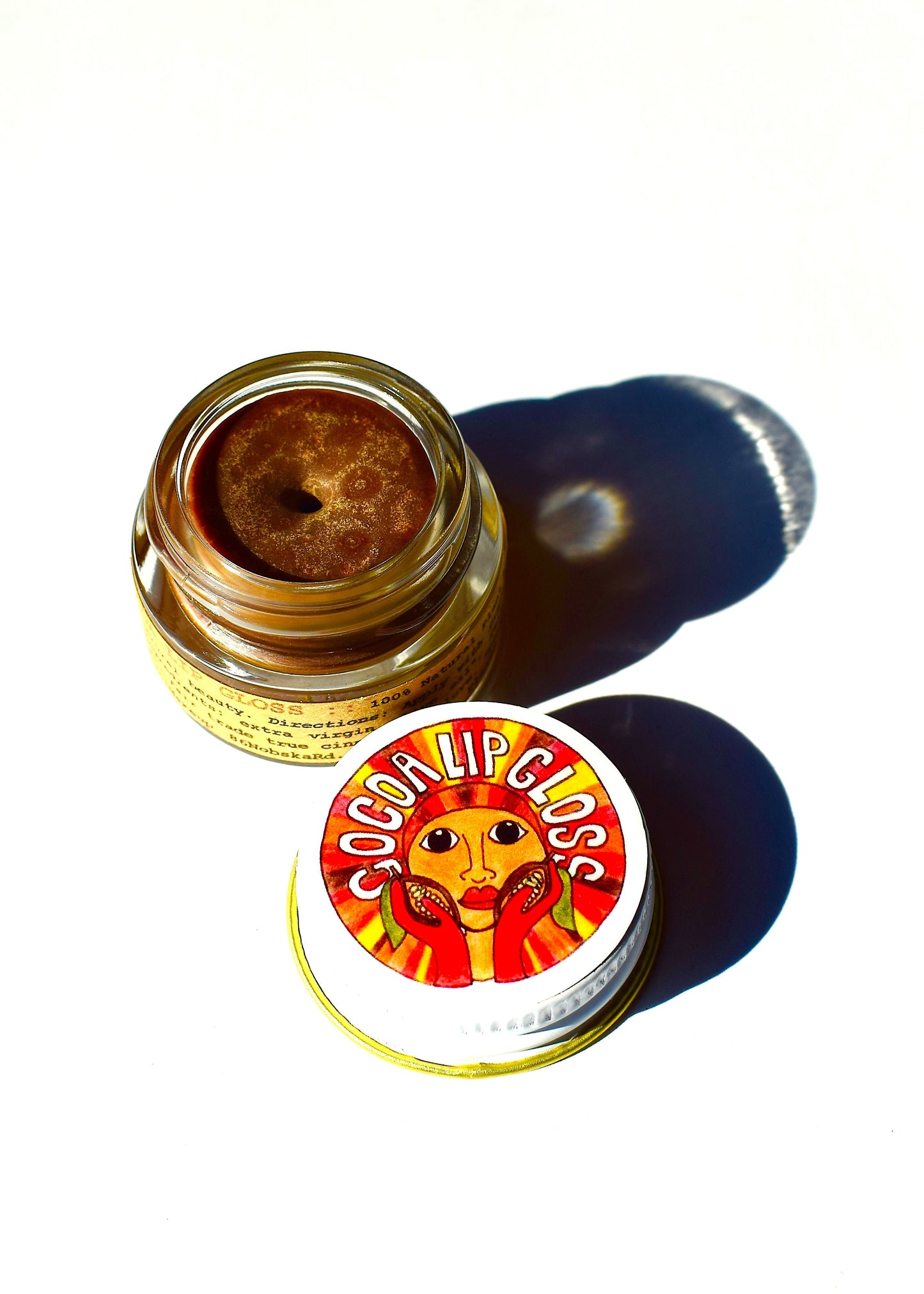 Cocoa Lip Gloss by Plant Makeup showing a shiny, smooth lip gloss tube with cocoa-colored product inside.