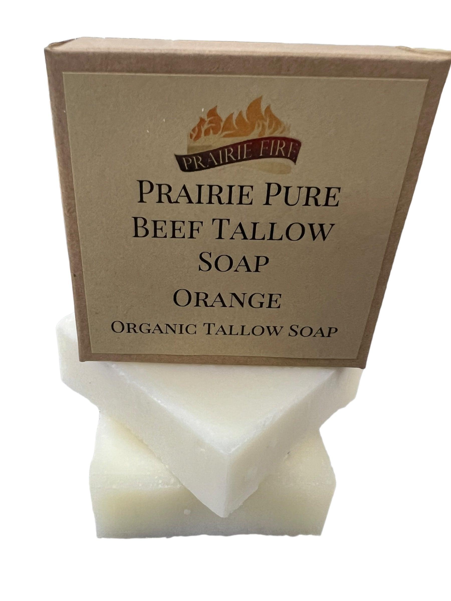 A brown Prairie Fire Tallow, Candles, and Lavender Pure Beef Tallow Soap Bar (3 Pack) box with a flame logo sits atop two white soap bars. The box highlights it’s natural, organic, and made in the USA from grass-fed beef tallow.