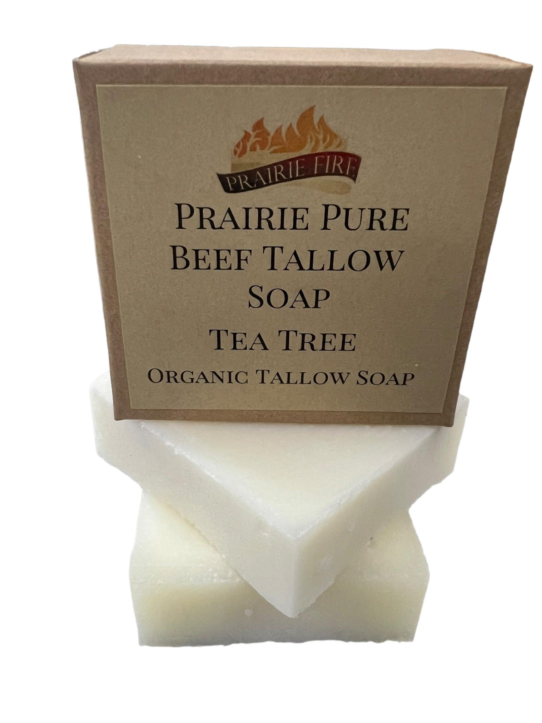 A Pure Beef Tallow Soap Bar by Prairie Fire Tallow, Candles, and Lavender in brown packaging is stacked on two unwrapped white bars; all are natural, organic, grass-fed soaps made in the USA for face, body, and hair.